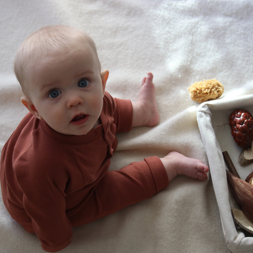 baby wearing sleepsuit in rust from The Sleepy Collection