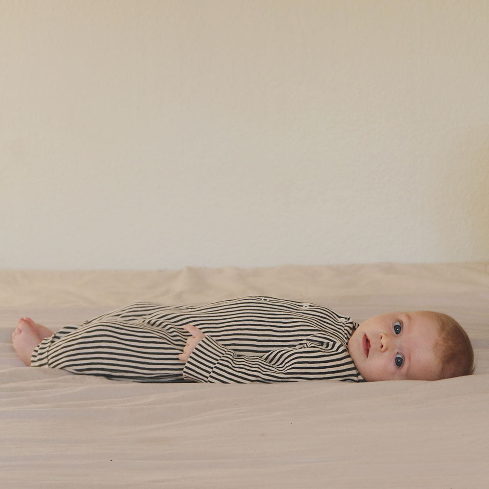 Little baby wearing striped baby sleepsuit in organic cotton from The Sleepy Collection